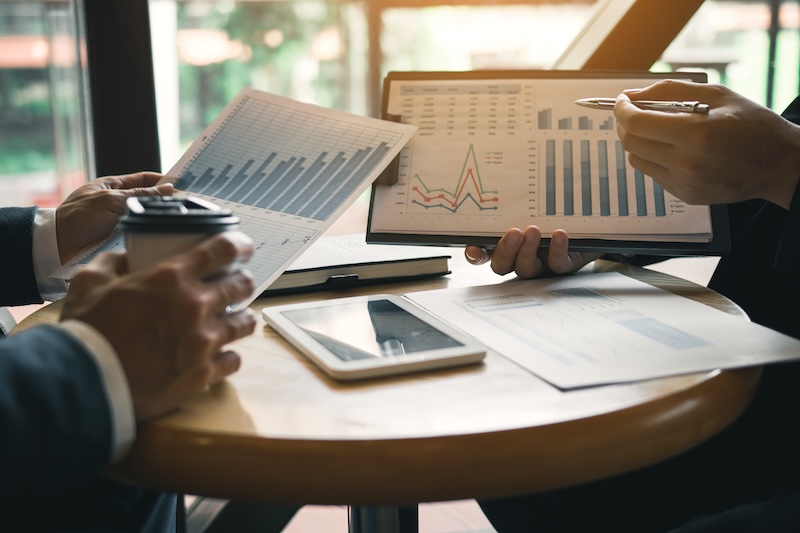 Businessmen pointed out the company performance chart on the table during the strategy discussion.